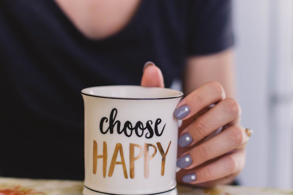 Happliness A woman holds a mug with 'choose happy' text indoors, promoting positivity.