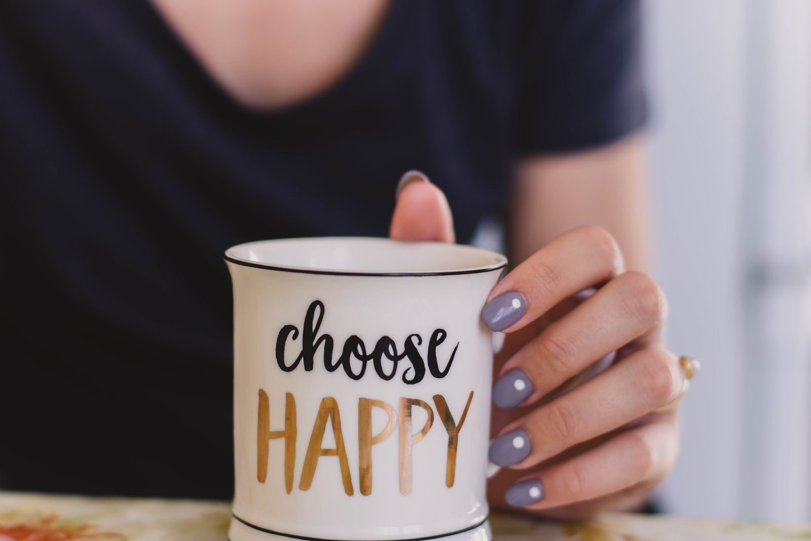 Happliness A woman holds a mug with 'choose happy' text indoors, promoting positivity.